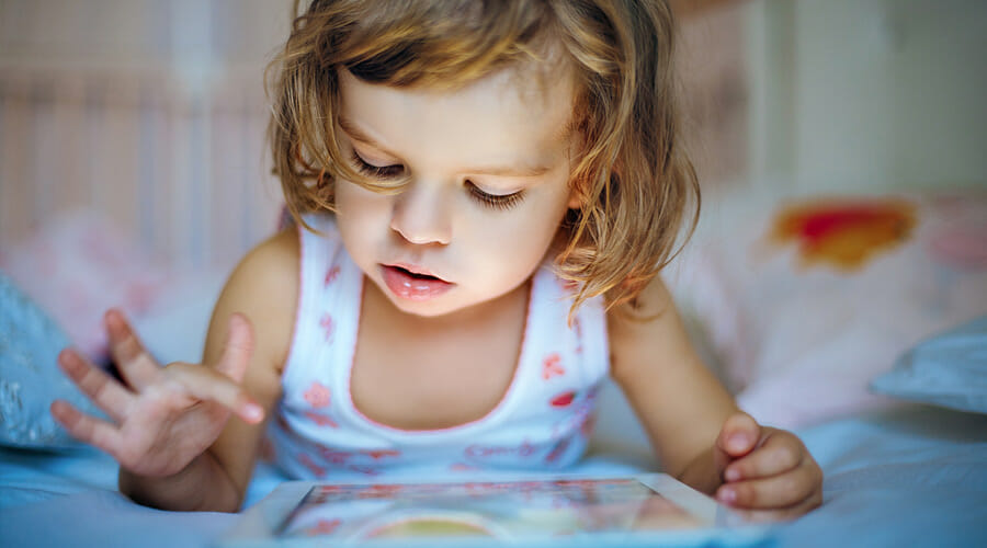 Blog-more-kids-gets-dry-eyes-due-to-electronic-gadget-use-Samer-Hamada-eye-clinic-london A child using an ipad