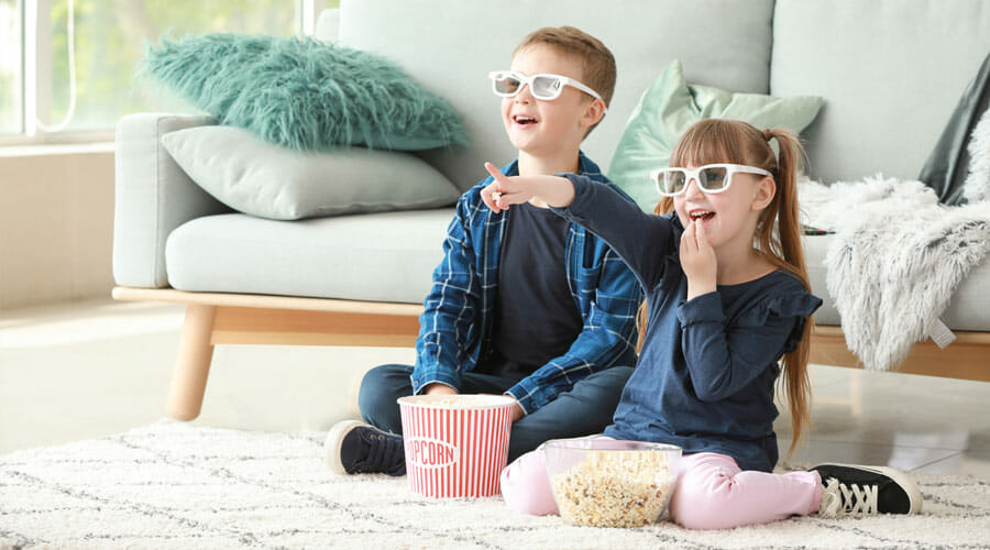 Children wearing 3D glasses, eating popcorn and watching a film