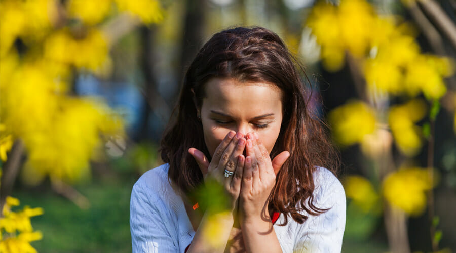 A woman sneezing into her hand