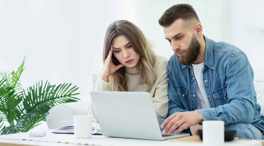 A couple staring at a laptop intently