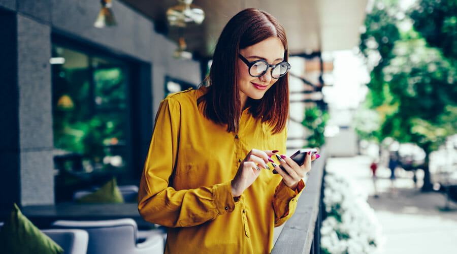 A young woman smiling whilst looking down at her phone