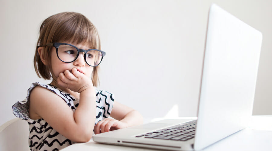 A child wearing glasses whilst looking at a laptop