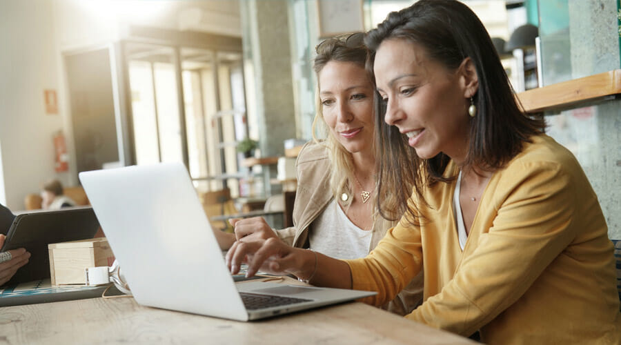 Two women using a laptop in a coffee shop