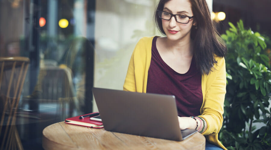 A woman with glasses using a laptop at a coffee shop