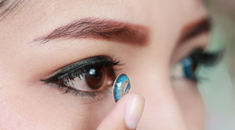 a woman inserting a halloween contact lens into her eye