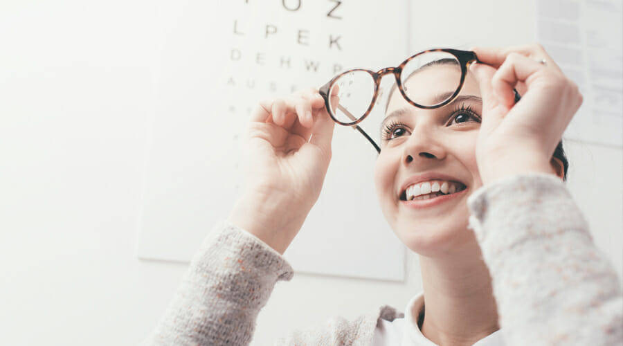 a woman holding her glasses up and looking into them