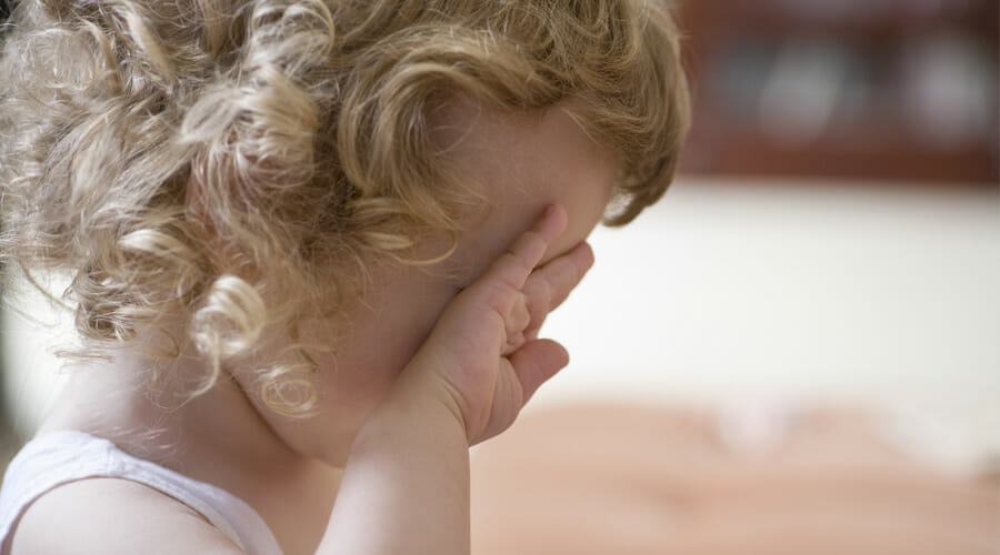 a little girl rubbing her eye with the back of her hand