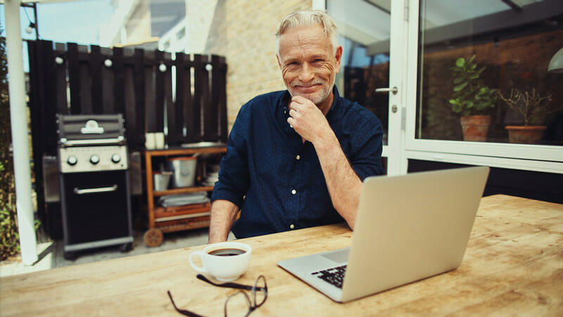 A man sat on a table outside smiling at the camera angle 2