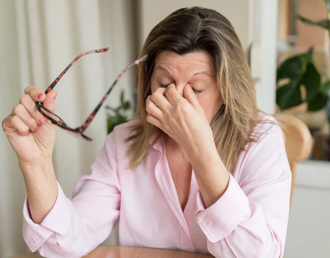 Woman with dry, tired eyes holding her glasses